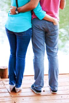 Backside of a couple hugging on the deck in the park