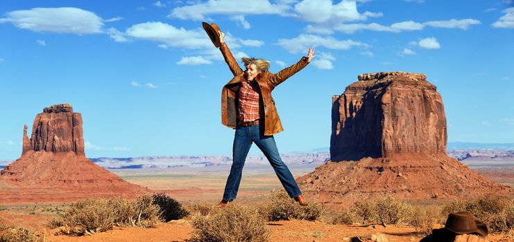 panoramic view of cowgirl jumping at Monument Valley, Utah, USA