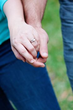 Close up picture of holding hands and engagement ring