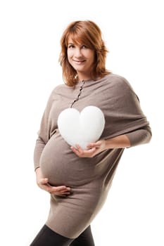 Beautiful pregnant woman standing on white background, holding a heart