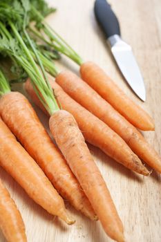 Fresh organic carrots on a wooden chopping board with knife