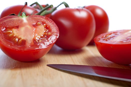 Fresh tomatoes being sliced on a wooden chopping board with knife