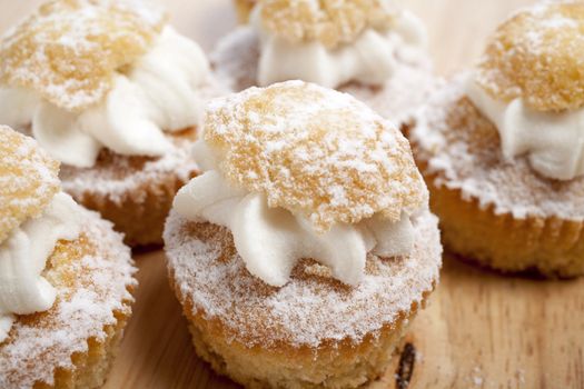 A group of fresh cakes with cream on wooden board