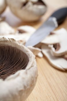 Fresh organic mushrooms being sliced on a wooden chopping board