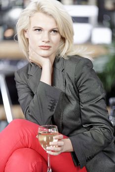 Attractive young woman enjoying a glass of white wine in a wine bar.