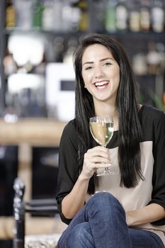 Attractive young woman enjoying a glass of white wine in a wine bar.