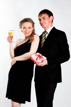 Portrait of a beautiful young couple with glasses of wine and a gift box with a red bow