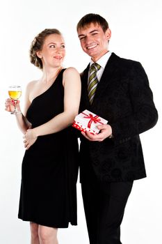 Portrait of a beautiful young couple with glasses of wine and a gift box with a red bow