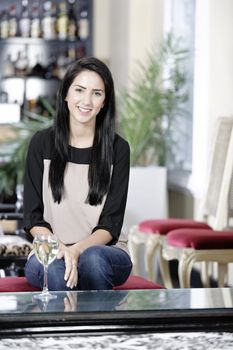 Attractive young woman enjoying a glass of white wine in a wine bar.