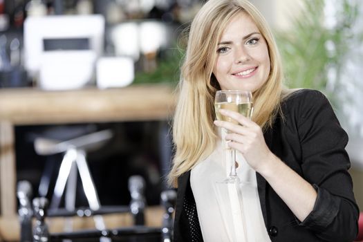 Attractive young woman enjoying a glass of white wine in a wine bar.