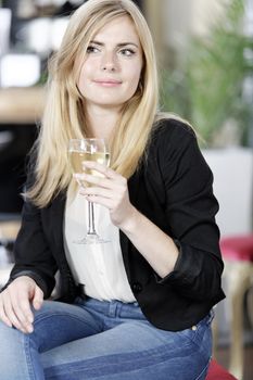 Attractive young woman enjoying a glass of white wine in a wine bar.