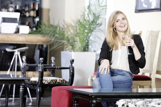 Attractive young woman enjoying a glass of white wine in a wine bar.