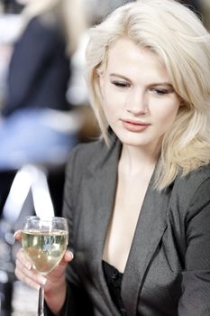 Attractive young woman enjoying a glass of white wine in a wine bar.