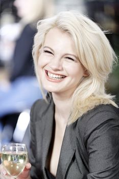 Attractive young woman enjoying a glass of white wine in a wine bar.