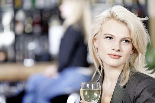 Attractive young woman enjoying a glass of white wine in a wine bar.