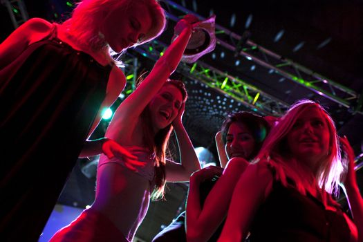 A group of female friends dancing on a nightclub dance floor.