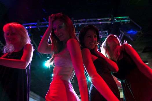 A group of female friends dancing on a nightclub dance floor.