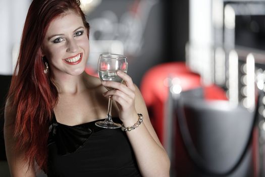 Beautiful young woman enjoying a glass of white wine at a bar.