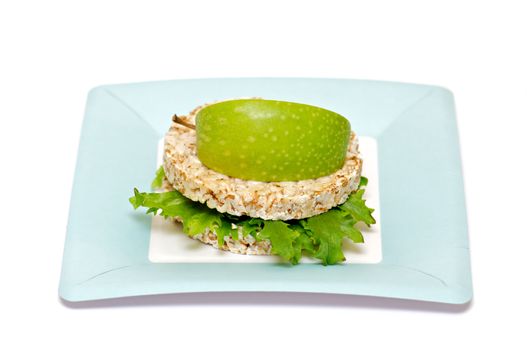 Gramineae Crispbread with Salad leaves and apple isolated on blue plate
