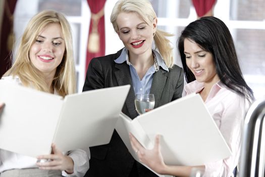 Three attractive work colleagues reading a wine list.