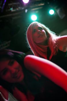A group of female friends dancing on a nightclub dance floor.