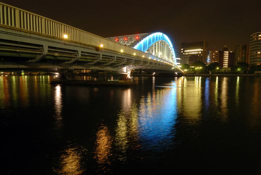 nighttime colorful reflection of Eitai Bridge illumination in waters of Sumida river at central part of Tokyo Metropolis, Japan