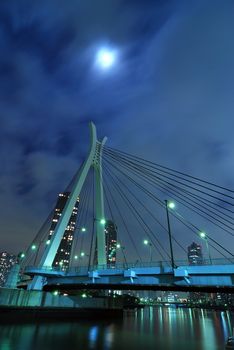 Chuo-Ohashi bridge in Tokyo, Japan by night with scattered moonlight behind moving clouds