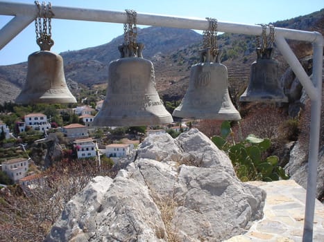 Hydra island bells on town and hills background                               