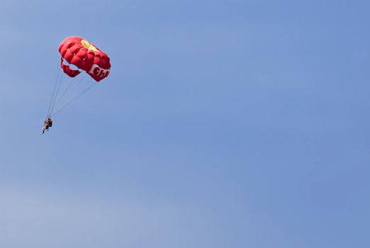 Couple doing a tandem parachute jump over deep blue background