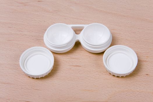 Set of compact lens case. On wooden background.