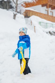 Cute little boy in blue riding on a sled near  the Austrian cottage