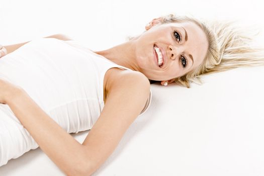 Attractive young woman in a white vest top sitting on the floor on white background