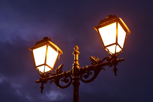Street Lamp Shining at Night against Dramatic Cloudy Sky