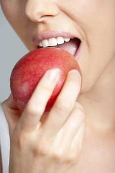 Beautiful young woman eating an apple wearing a white vest top