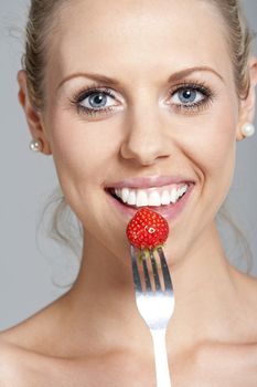 Beautiful young woman eating fresh summer berries