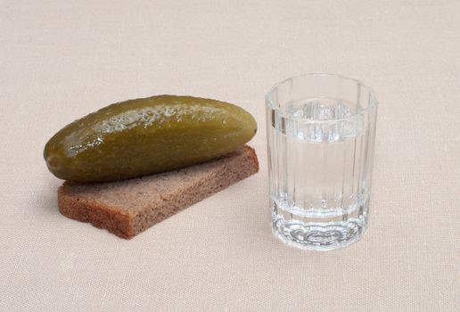 Wine-glass of vodka a piece of rye bread and a cucumber