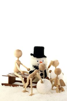 family with two children as a wooden dolls builds a snowman