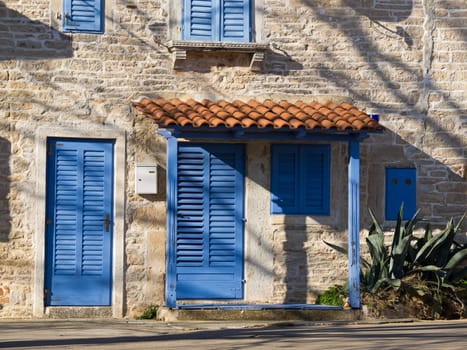 stone house with blue door and windows and agava 