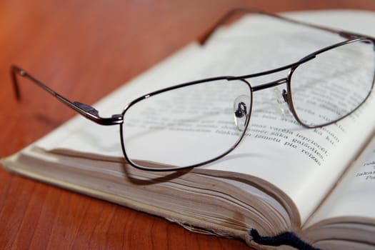 Old books with glasses lay on a table.