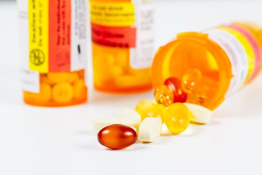 Colorful vitamins spilling from prescription bottle with warnings