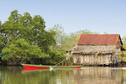 Local man rowing through water village, Ream National Park, Cambodia, Southeast Asia