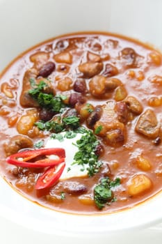 Hot soup in the white dish on wooden table