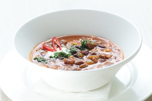 Hot soup in the white dish on wooden table