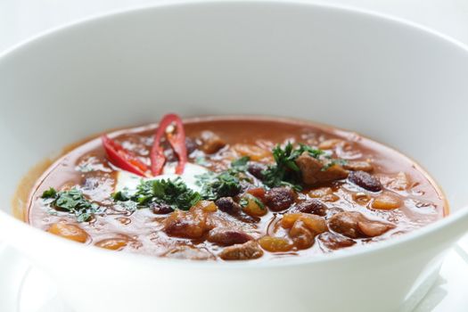 Hot soup in the white dish on wooden table