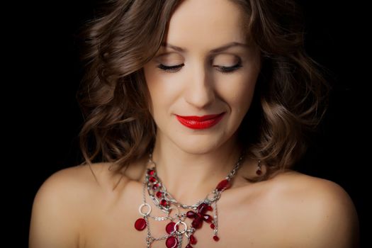 Closeup portrait of young beautiful girl with makeup in red on a black background