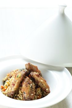 Peaces of meat with millet in the white dish