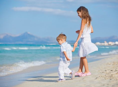 Young beautiful girl and boy playing happily at pretty beach. Majorca