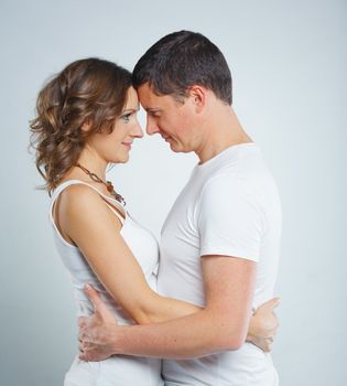 Happy beautiful young couple in love in white casual clothing. In the studio