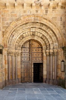 Architectural detail of an old church door in Avila, Spain with beautiful beige stone detail, arches and columns.