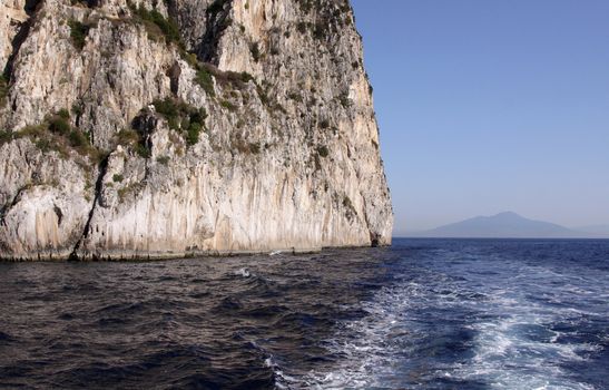 A cliff face on the island of Capri and Mount Vesuvius in the background.  (Italy)
